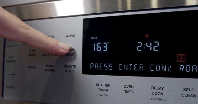 Close view of a person adjusting settings on a Thermador wall oven.