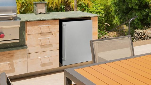 Front view of a modern outdoor kitchen with a freestanding Danby refrigerator