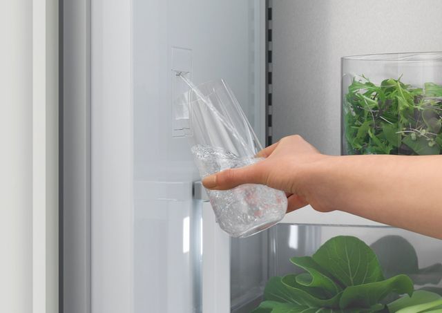 Front view of someone using the internal water dispenser in a Fisher & Paykel refrigerator