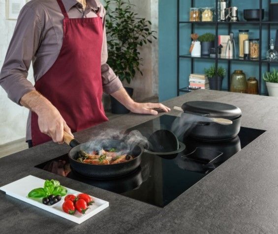Credit: Elicia Front view of a man cooking dinner on an induction downdraft cooktop