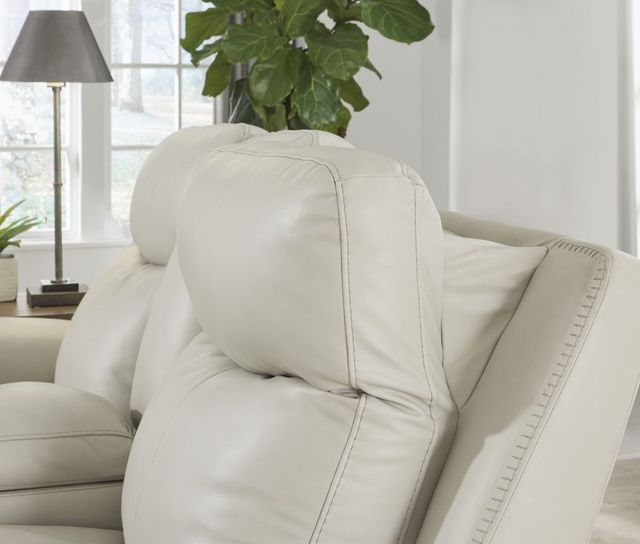 close view of a white leather recliner chair with an adjustable headrest leaned forward