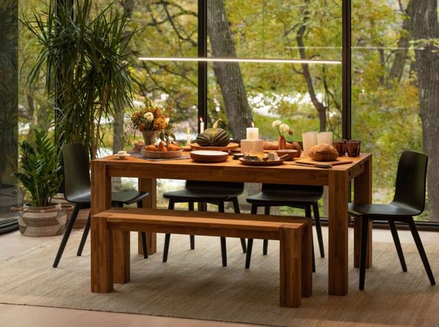 Front view of a modern dining room with Palliser furniture and with large window walls and various greenery outside