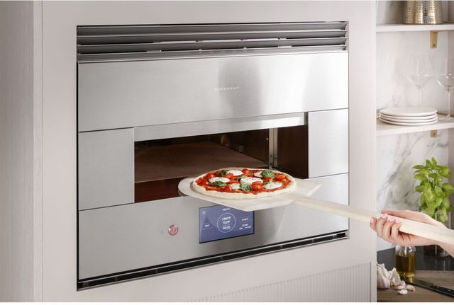 front view of a Monogram hearth oven with pizza being placed inside