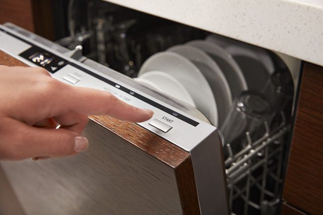 Credit: Whirlpool Front view of a modern panel-ready 18-inch dishwasher as a person presses the start button
