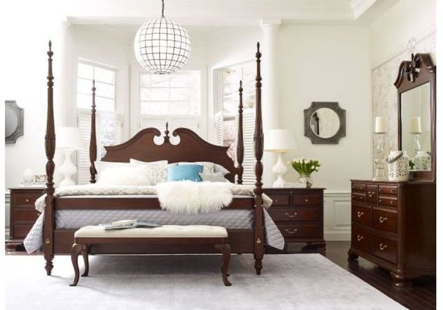 Front view of a traditional style wooden poster bed in a modern bedroom