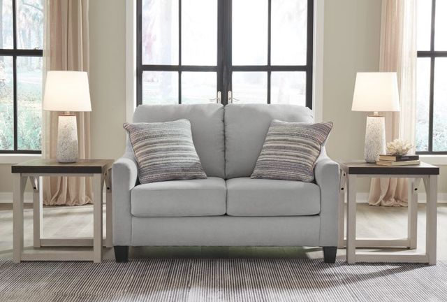 Front view of a modern living room with a grey loveseat between two end tables