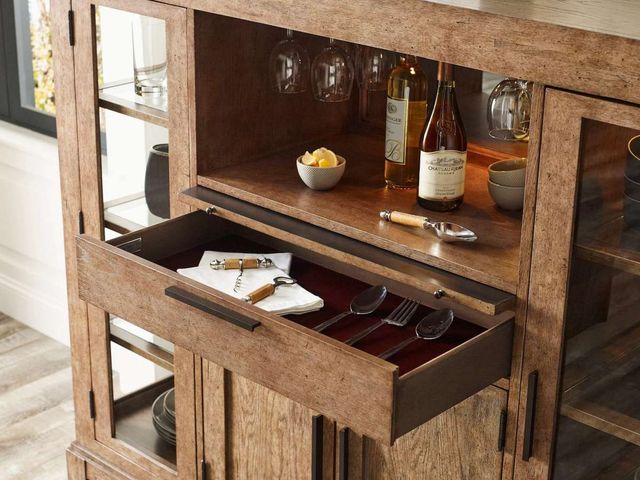 Front view of a modern home bar cabinet with shelving, glass storage, a drawer pulled out, and other various bar storage solutions.
