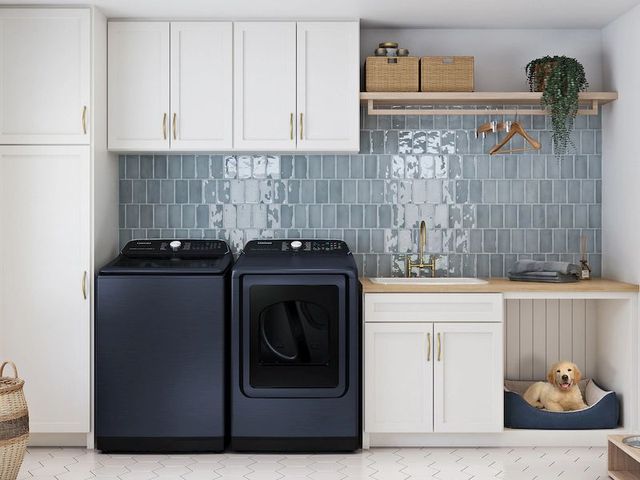 Front view of a modern laundry room with white cabinetry and a blue washer and dryer. 