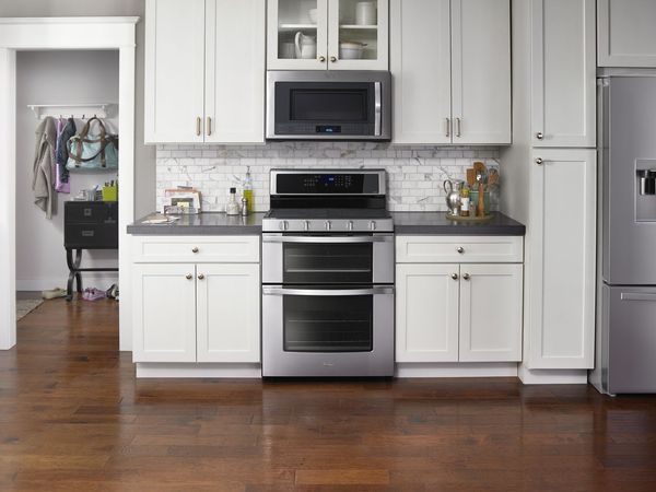 A person placing a dish in the lower oven of a double oven range A person placing a dish in the lower oven of a double oven range