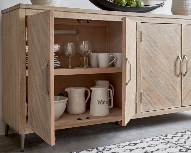 close view of an opened light wooden sideboard with various glassware and ceramic dishes inside