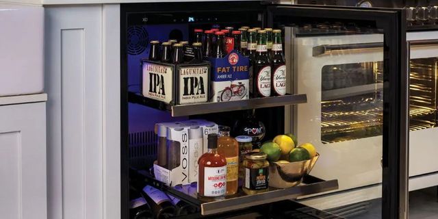 front view of an opened beverage refrigerator with the drawers pulled out and beverages on the shelves