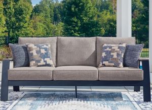 Woven outdoor sofa with light gray cushions in an outdoor setting Woven outdoor sofa with light gray cushions in an outdoor setting