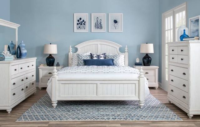 front view of a transitional bedroom with a white low four-poster bed and a matching dresser and nightstands